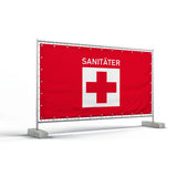 Bauzaunbanner - ein rotes Banner, das an einem Bauzaun befestigt ist, mit der weißen Aufschrift Sanitäter und einem roten Kreuz auf einem weißen Quadrat.