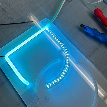 Montage eines hellblauen LED Neon Flex Streifens auf einer gefrästen Acrylplatte. Einblick in die maßgeschneiderte Produktion.