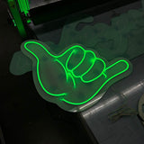 Grün leuchtendes LED Neon Schild in Form einer Shaka-Hand auf Acrylglas. Maßgeschneiderte Leuchtwerbung für Events.