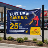PVC Werbebanner an einer Tankstelle mit der Aufschrift „Fuel up & Save Big“. Das robuste Banner ist mit Ösen und Spannseilen zwischen zwei schwarzen Metallpfosten befestigt und bewirbt eine Rabattaktion von Pine Ridge Fuel & Mart.