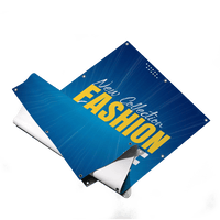 Ein teilweise aufgerolltes PVC Werbebanner in leuchtendem Blau mit einem strahlenförmigen Hintergrundmuster. Auf der Plane steht in auffälliger gelber und weißer Schrift "New Collection FASHION SALE". Am Rand sind silberne Metallösen zur Befestigung eingelassen und die umgeschlagene Ecke zeigt die weiße Rückseite des Materials.