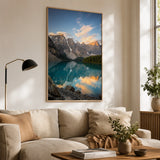 Poster drucken – ein großes, gerahmtes Poster mit einer beeindruckenden Berglandschaft und einem spiegelnden See, das als stilvolle Wanddekoration über einem hellen Sofa in einem gemütlichen Wohnzimmer hängt.
