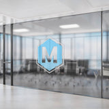 Transparente Fensteraufkleber mit blauem Hexagon-Logo und dem Buchstaben M auf einer Konferenzraum-Glaswand.