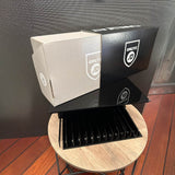 Eine teilweise geöffnete Schiebeschachtel aus bedruckter Wellpappe, die auf einem schwarzen Displayständer liegt. Der äußere Schuber ist schwarz bedruckt, der innere Karton ist naturbraun. Beide Verpackungsteile sind mit dem weißen Logo „ONLY AT JD“ versehen.