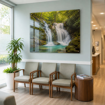 Acrylglas bedrucken als großformatiges Wandbild in einem Wartezimmer. Das Motiv zeigt einen idyllischen Wasserfall im Wald. Das Schild ist mit unauffälligen Halterungen an der Wand montiert und sorgt durch die Tiefenwirkung des Acrylglases für eine entspannte Atmosphäre im Raum.