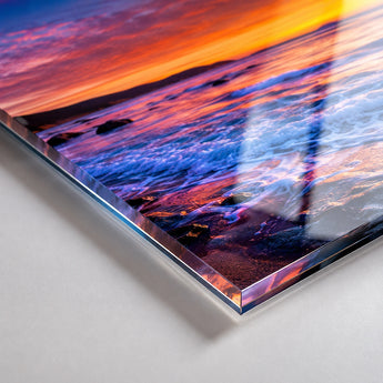 Acrylglas bedrucken in der Detailansicht, die die beeindruckende Tiefe des Direktdrucks zeigt. Die Makroaufnahme hebt die polierte, gläserne Kante und die Lichtbrechung im Material hervor, während das Sonnenuntergang-Motiv durch die glänzende Oberfläche besonders farbintensiv wirkt.