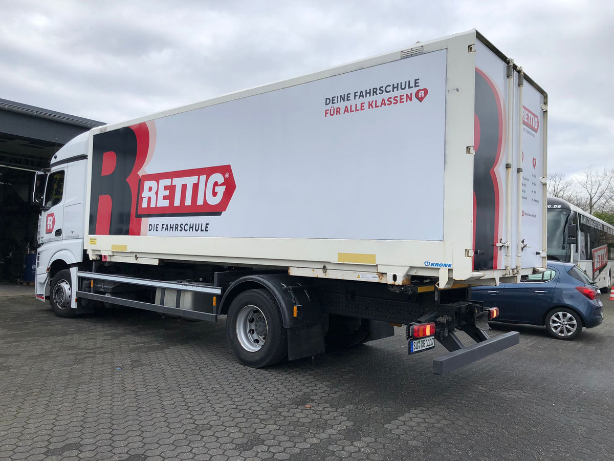 Fahrzeugbeschriftung eines LKW mit großflächiger Werbefolierung und Logo der Fahrschule Rettig auf der Seitenfläche des Aufbaus.