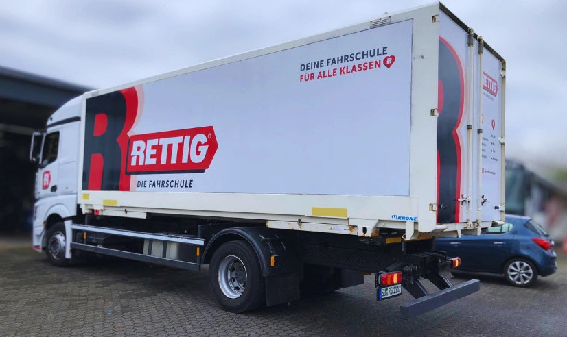 Fahrzeugbeschriftung eines LKW mit großflächiger Werbefolierung und Logo der Fahrschule Rettig auf der Seitenfläche des Aufbaus.