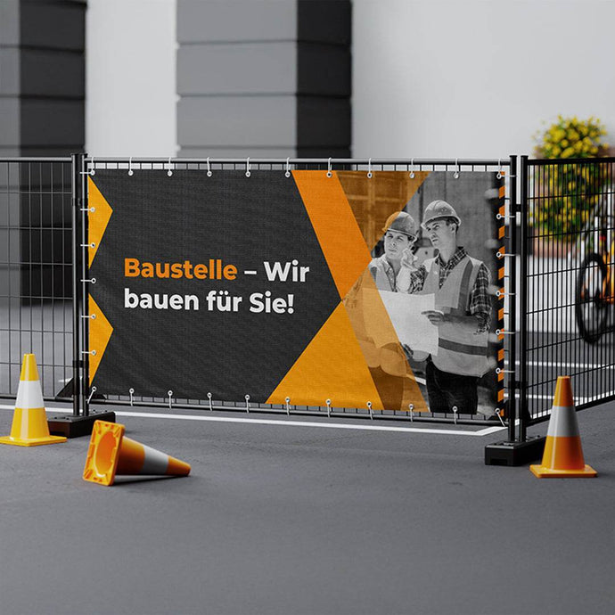 Winddurchlässiges Mesh-Banner auf einem Bauzaun bei starkem Tageslicht