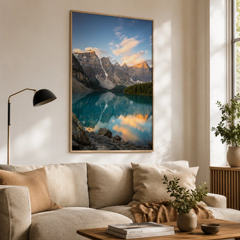Poster drucken – ein großes, gerahmtes Poster mit einer beeindruckenden Berglandschaft und einem spiegelnden See, das als stilvolle Wanddekoration über einem hellen Sofa in einem gemütlichen Wohnzimmer hängt.