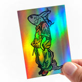 Eine Hand hält einen rechteckigen, holografischen Aufkleber mit starkem, regenbogenfarbenem Schimmer. Das als schwarze Linienzeichnung gedruckte Motiv zeigt einen Comic-Fisch im Streetwear-Look mit weiten Hosen, T-Shirt und Rucksack. Ein kreatives Beispiel dafür, wie Illustrationen wirken, wenn man sie als auffällige Sticker drucken lässt.