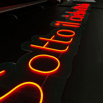 Rot-orange leuchtende LED Neon Schrift auf einer transparenten Acrylglas-Platte. Maßgeschneiderte Leuchtwerbung.