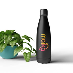 Thermobecher bedrucken – Eine matte, schwarze Isolierflasche mit dem farbenfrohen „maika“ Logo im Farbverlauf neben einer grünen Zimmerpflanze im türkisen Topf auf weißem Grund.