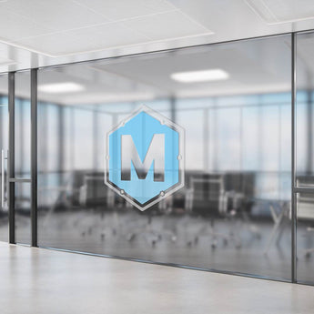 Transparente Fensteraufkleber mit blauem Hexagon-Logo und dem Buchstaben M auf einer Konferenzraum-Glaswand.
