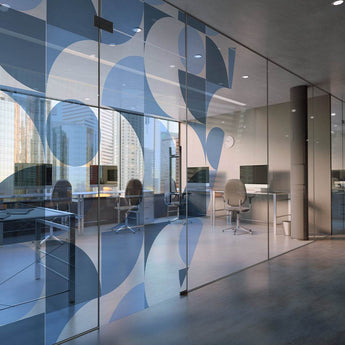 Transparente Fensteraufkleber mit blauem, abstrakt-geometrischem Muster auf einer großen Büro-Glaswand.