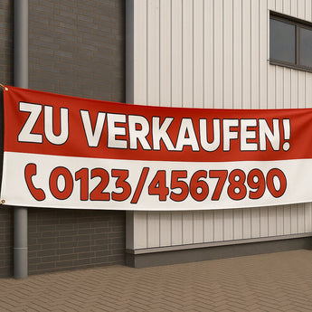 Ein rot-weißes "Zu Verkaufen" Werbebanner, befestigt an einer modernen Gebäudefassade. Passende Roll-Up Banner drucken.